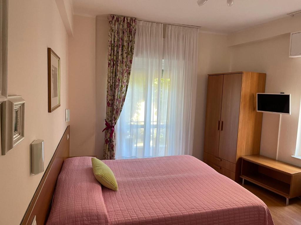 1 dormitorio con 1 cama con manta roja y ventana en Hotel Stazione del Sole, en Albenga