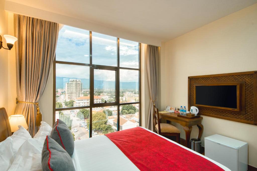 モシにあるKibo Palace Hotel Moshiのベッドと大きな窓が備わるホテルルームです。