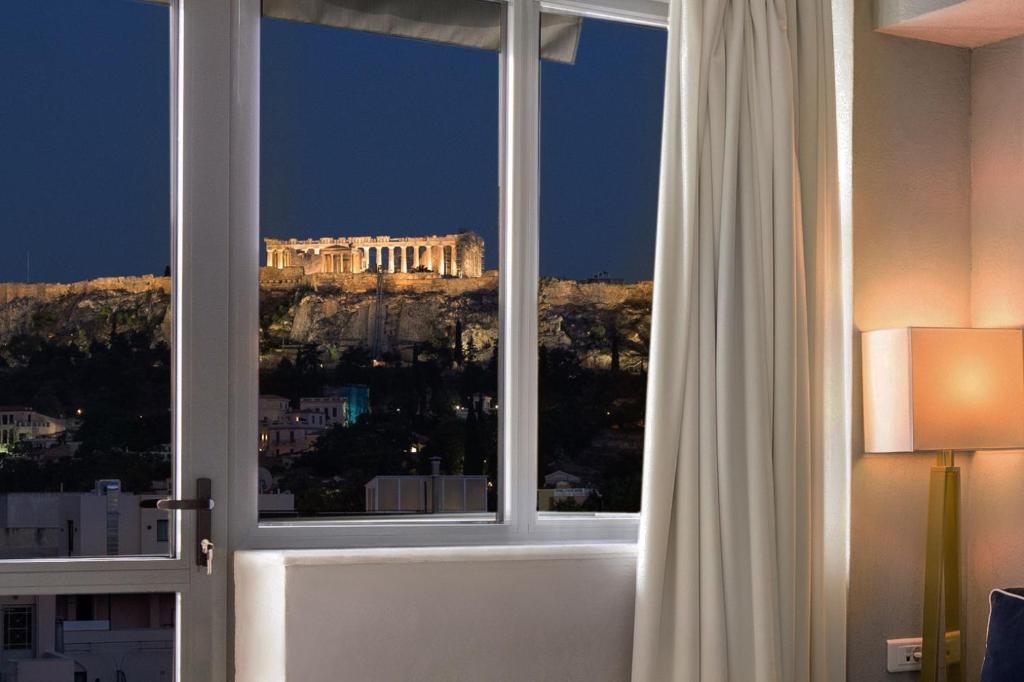 a view of the acropolis from a window in a hotel room at Downtown Athens Lofts - The Acropolis Observatory in Athens