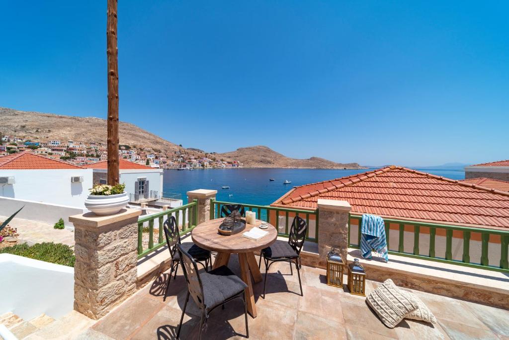 un patio con mesa, sillas y el océano en Muse Clio, en Halki