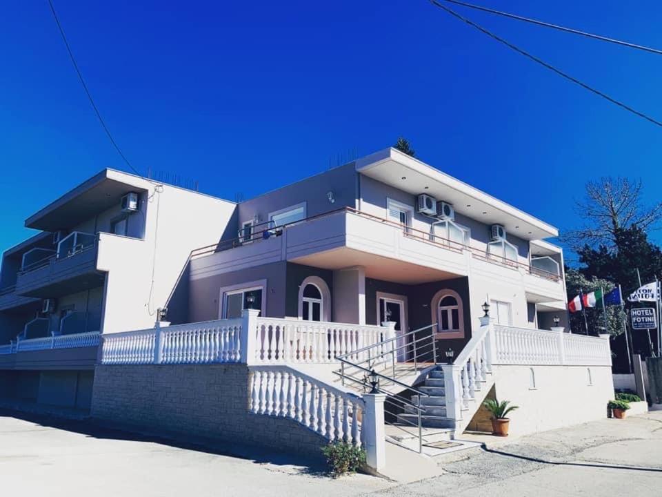 a large white house with a staircase in front of it at Hotel Fotini in Mytikas