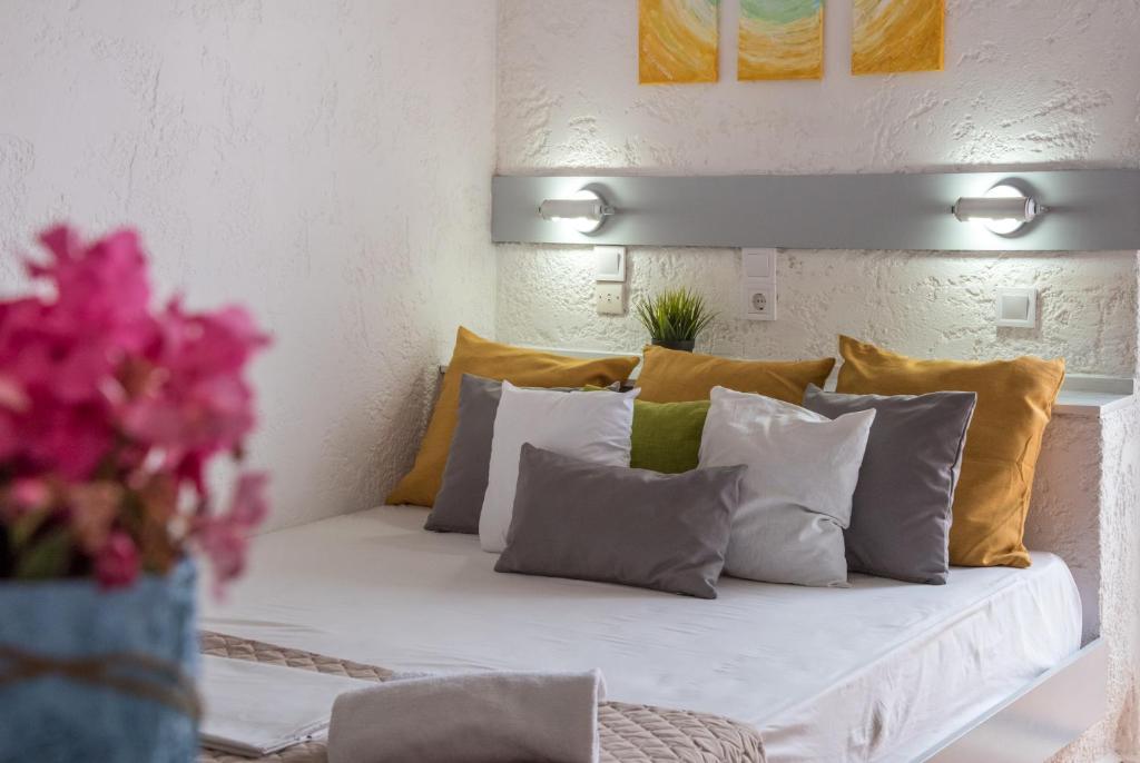 ein Bett mit gelben und weißen Kissen und einer Blumenvase in der Unterkunft Amazona in Agia Pelagia