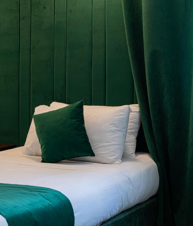 a bed with a green wall and white pillows at Hotel Majestic in Casablanca