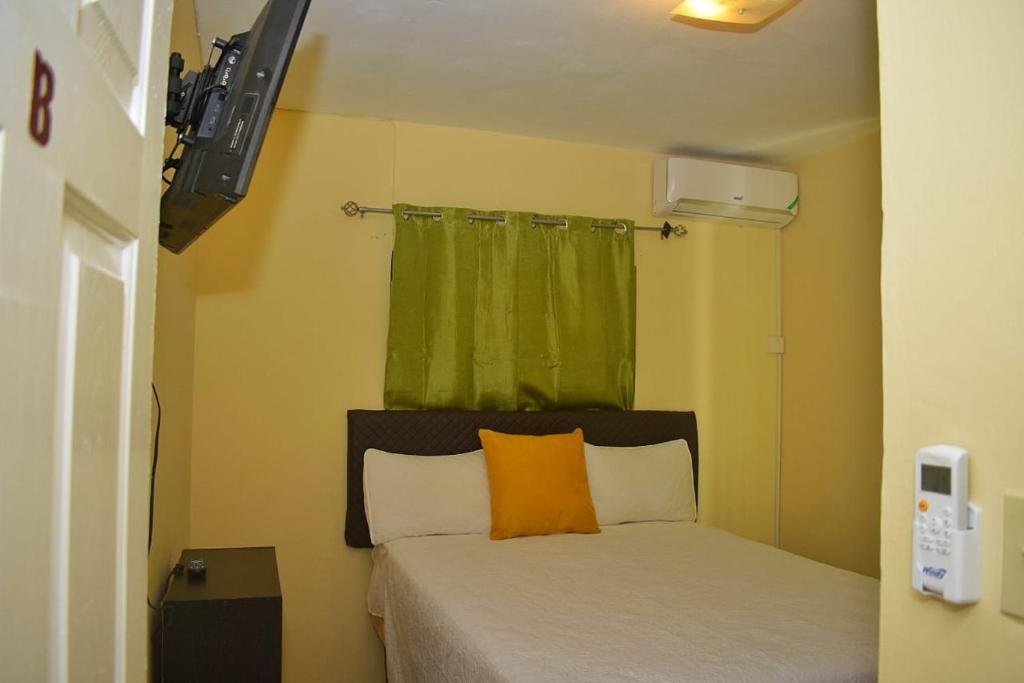 a small bedroom with a bed with an orange pillow at Unity Villa Near Montego Bay and Beaches free WiFi 2bedrooms in Montego Bay