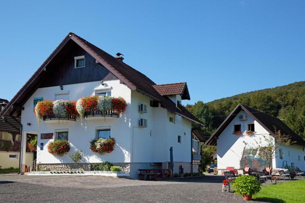 um edifício branco com flores nas janelas em House Pox em Plitvicka Jezera