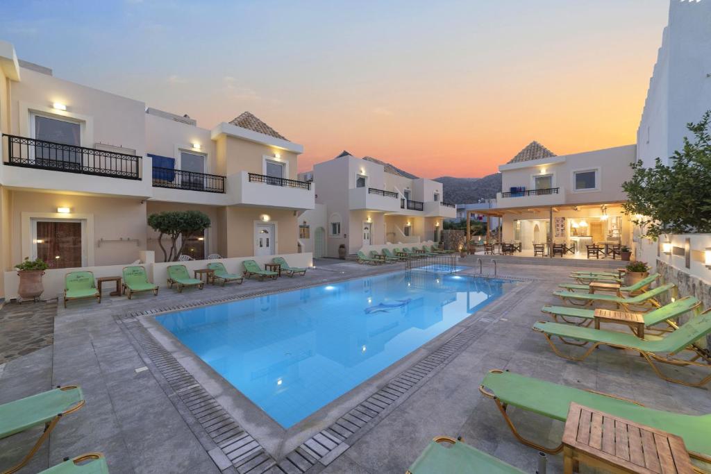 a large swimming pool in a resort with lounge chairs at Olive Grove Apartments in Elounda