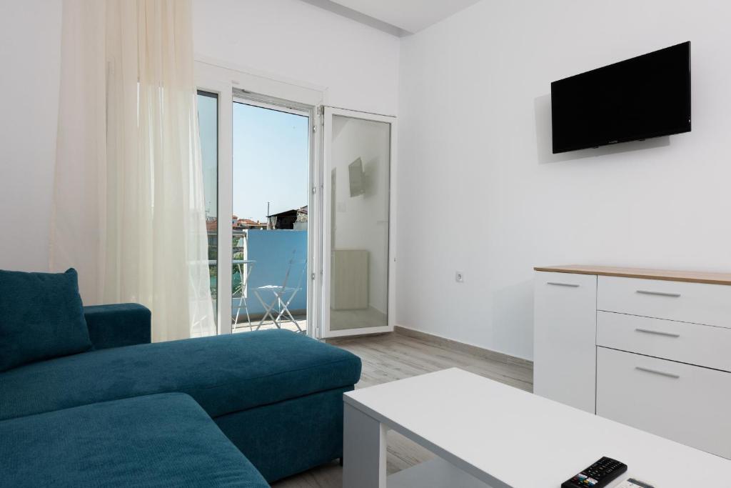 a living room with a blue couch and a tv at Diamanti Apartments Downtown Limenas Thasos in Limenas