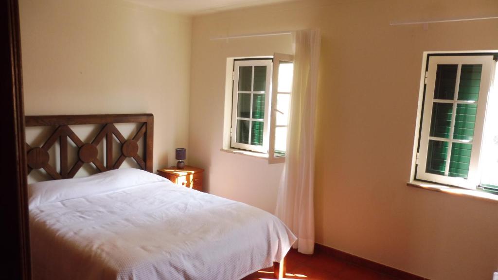 a bedroom with a white bed and two windows at GBT Quartos in Sines
