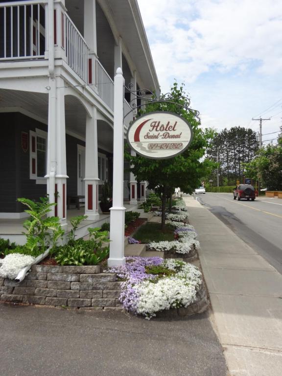 a sign in front of a building with flowers at Hotel Saint-Donat in Saint-Donat-de-Montcalm