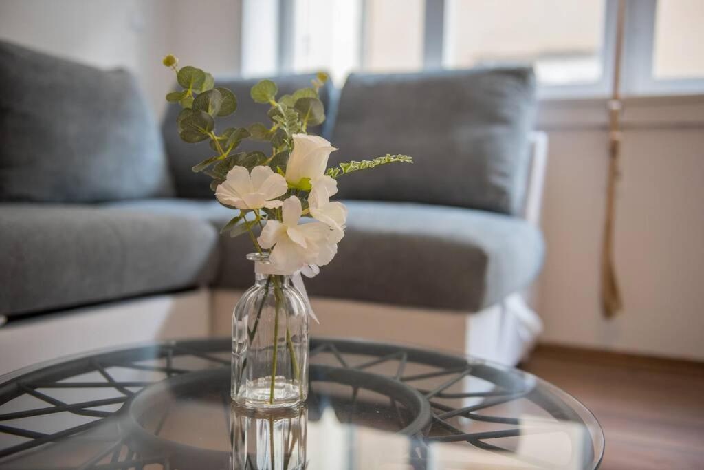 a glass vase with flowers on a glass table at Central View Zadar in Zadar
