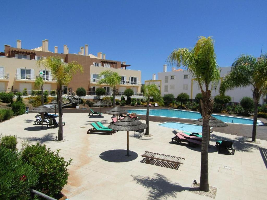 ein Resort mit einem Pool, Palmen und Gebäuden in der Unterkunft Apartamento Duplex - Cabanas Garden in Tavira