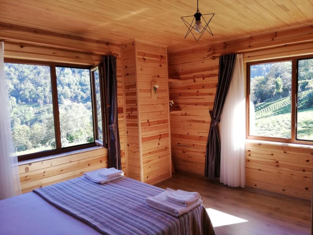 1 dormitorio con 1 cama en una habitación de madera con ventanas en Viceminiotel, en Rize