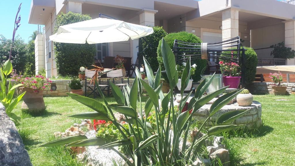 un giardino con ombrellone e alcune piante di Modern Villa in Chania a Perivólia