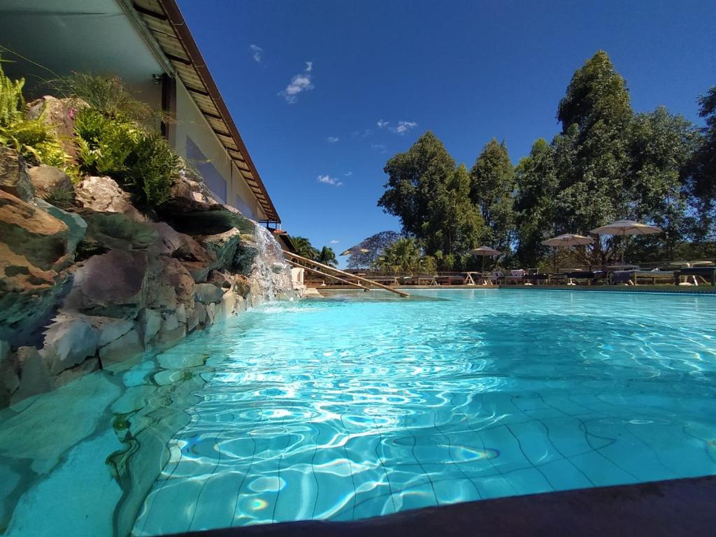 a swimming pool with blue water in a resort at Village Resort in Jaboticatubas