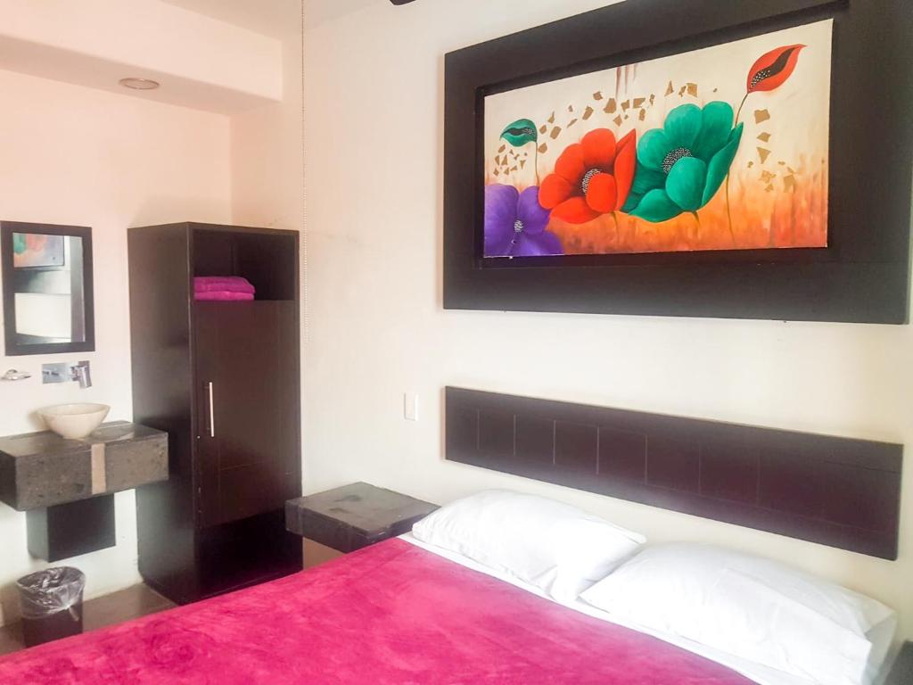 a bedroom with a pink bed and a painting on the wall at Hotel Palacio By Rotamundos in Río Grande