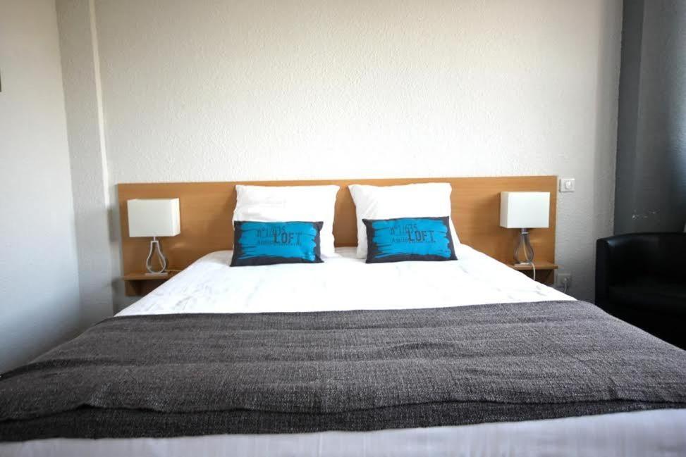 a bedroom with a large bed with two blue pillows at Hôtel la Régie in Briey