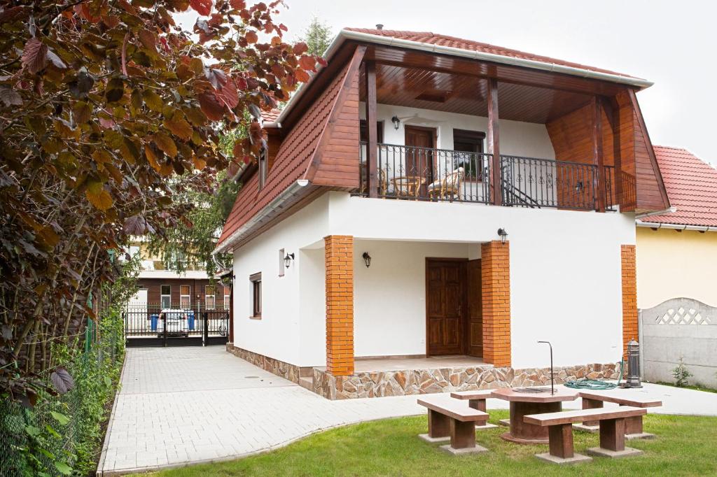 a house with two benches in front of it at Négy évszak apartmanház in Mezőkövesd