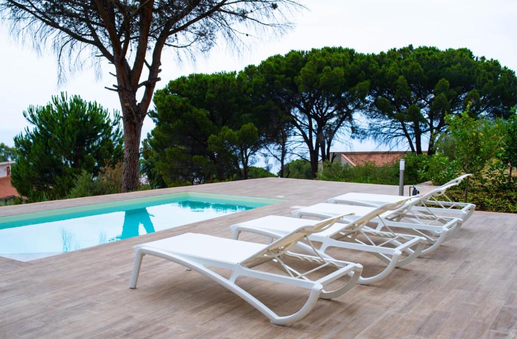 een rij ligstoelen naast een zwembad bij La Villetta di Cefalù in Cefalù