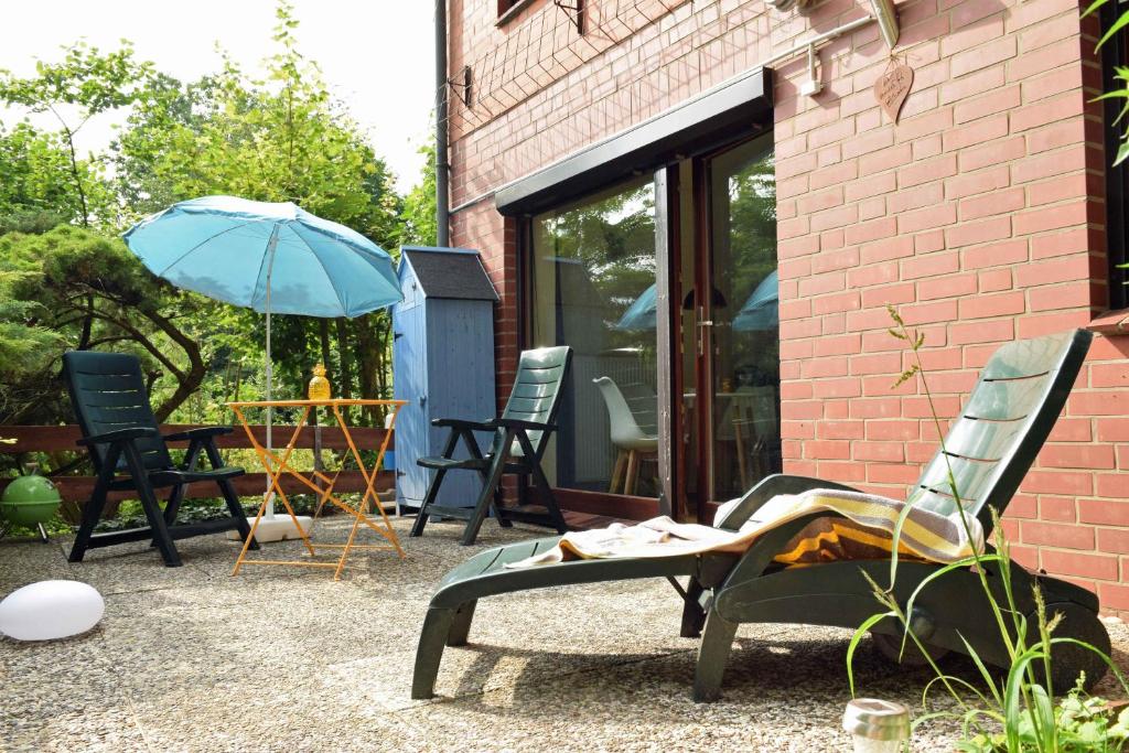 eine Terrasse mit Stühlen und einem Tisch mit einem Sonnenschirm in der Unterkunft Elbwald-Studio in Hitzacker
