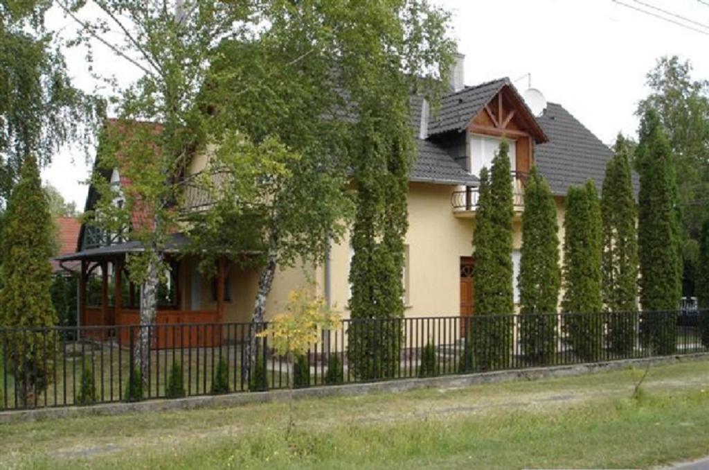 a house with a fence in front of it at 14 férőhelyes ház saját stéggel, játszótérrel Balatonfenyvesen vízparti utcában in Balatonfenyves