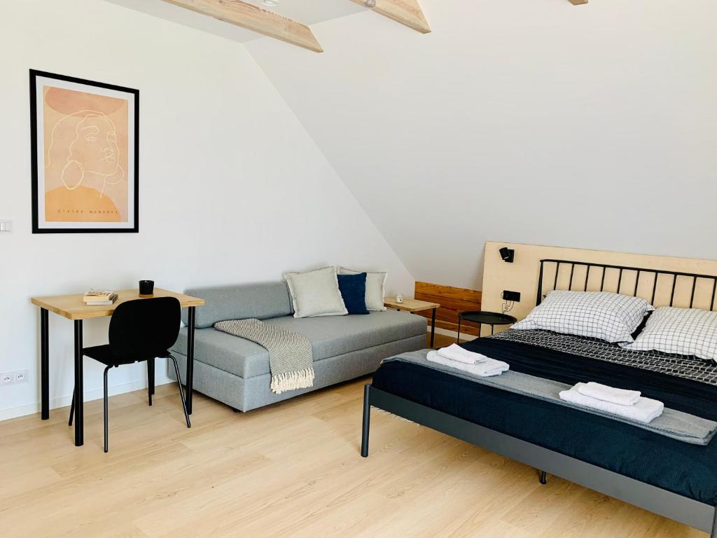 ein Schlafzimmer mit einem Bett, einem Sofa und einem Tisch in der Unterkunft Apartamenty KAHOY balia pomost Kozin in Kozin