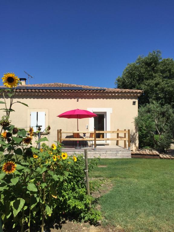 une maison avec une table et un parapluie rose dans l'établissement L’ escapade, à Mallemort