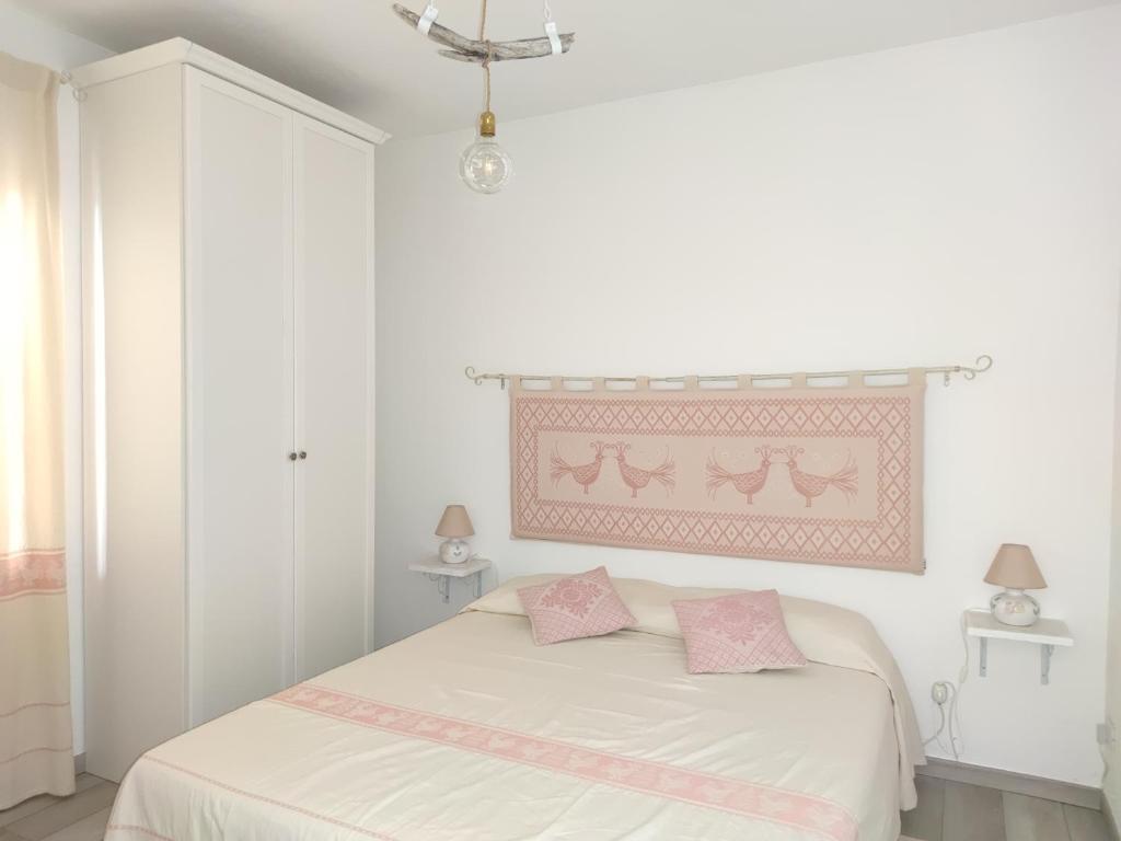 una camera bianca con letto e cuscini rosa di I love Ogliastra Apartments a Bari Sardo