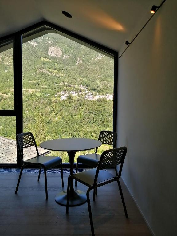 stół i krzesła w pokoju z dużym oknem w obiekcie V&V RentRoom Design w mieście Gignod