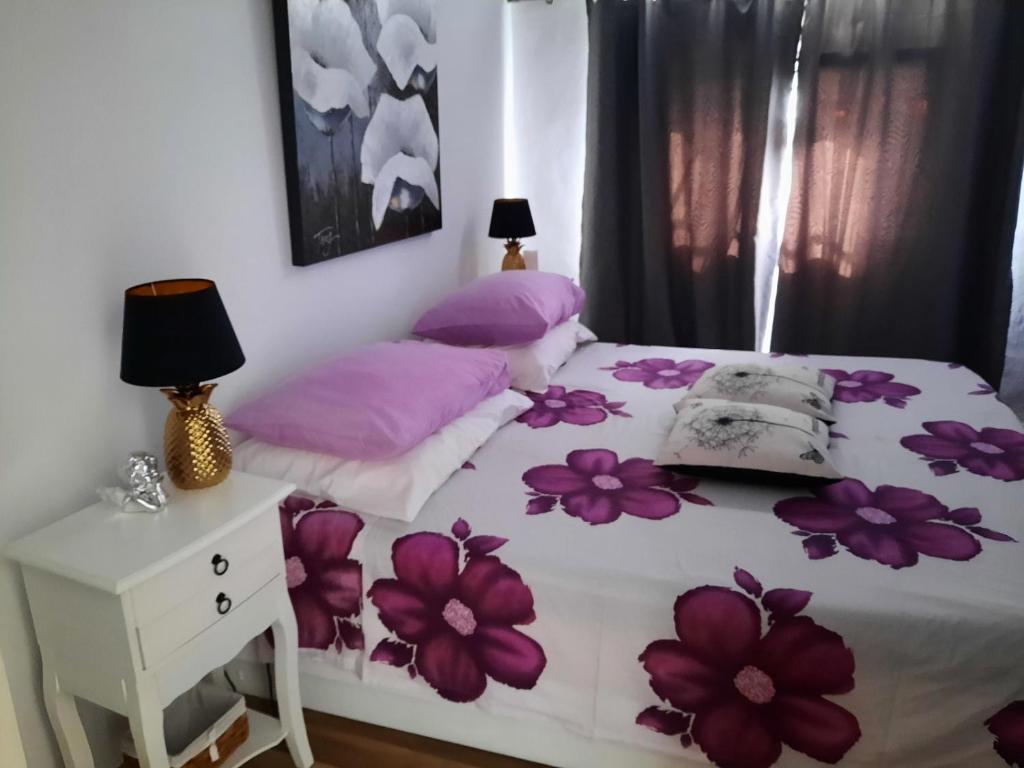 a bedroom with a bed with purple flowers on it at Apartment Lavanda in Mali Lošinj