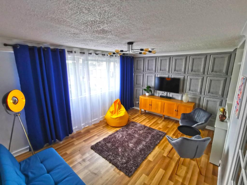 a living room with blue curtains and a blue couch at Glasgow Apartment Cozy and ultramodern in Glasgow