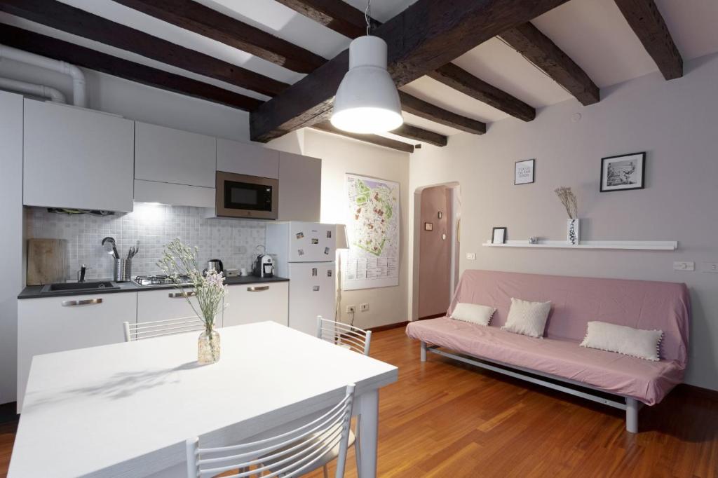 eine Küche und ein Wohnzimmer mit einem rosa Sofa in der Unterkunft Rua Freda Apartments in Modena