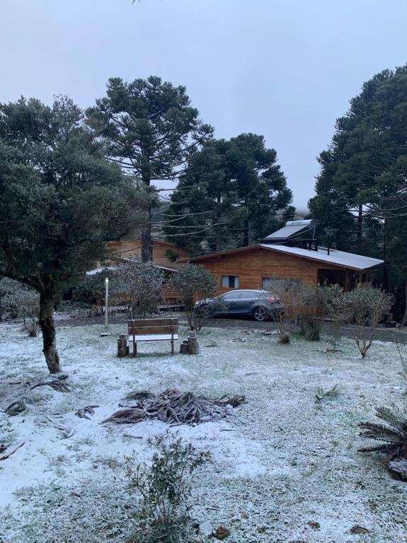 a snow covered yard with a bench in front of a house at Casa em Urubici Sítio Pássaro D'água in Urubici