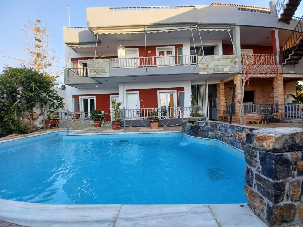 uma casa com piscina em frente a uma casa em Gouves Sunset apts em Gouves
