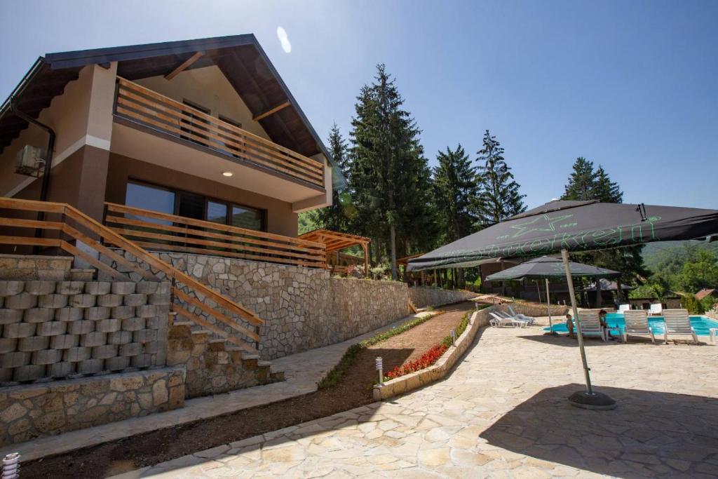 een huis met een parasol naast een zwembad bij Vikendica Bjelašnica in Sarajevo