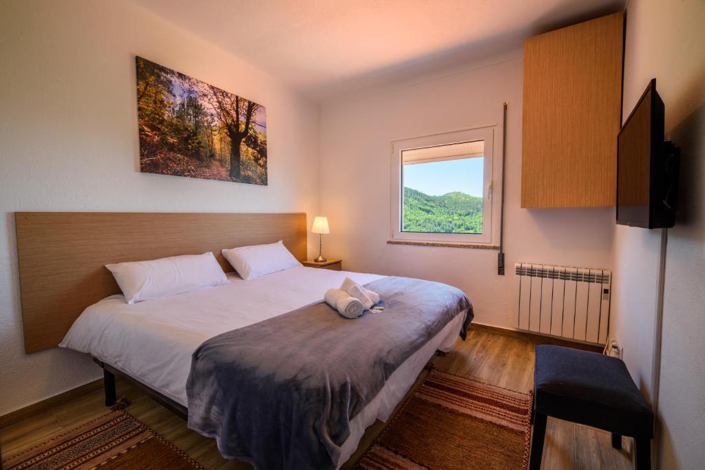 a bedroom with a large bed and a window at Casa do Beco - Fabulous 3 Bedroom House with an Office, Seia, Serra da Estrela 