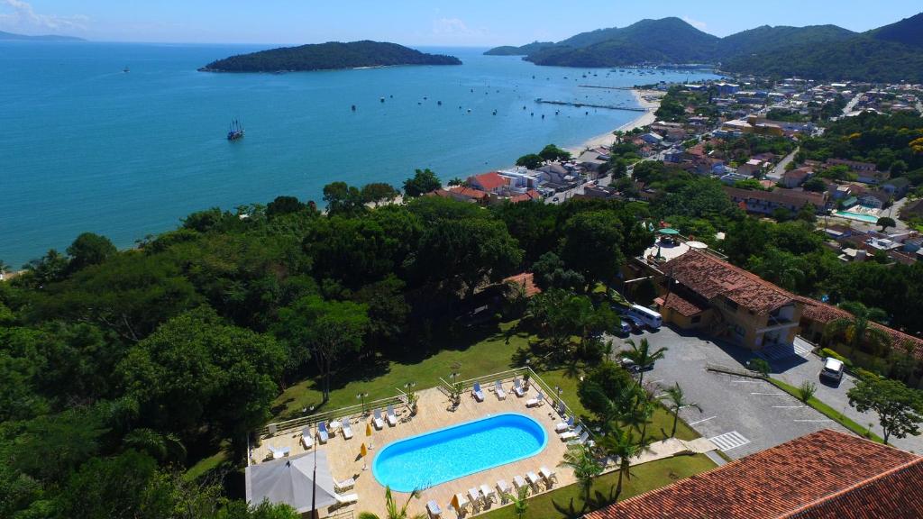Morro do Sol Hotel & Eventos في بورتو بيلو: اطلالة جوية على منتجع مع مسبح وشاطئ