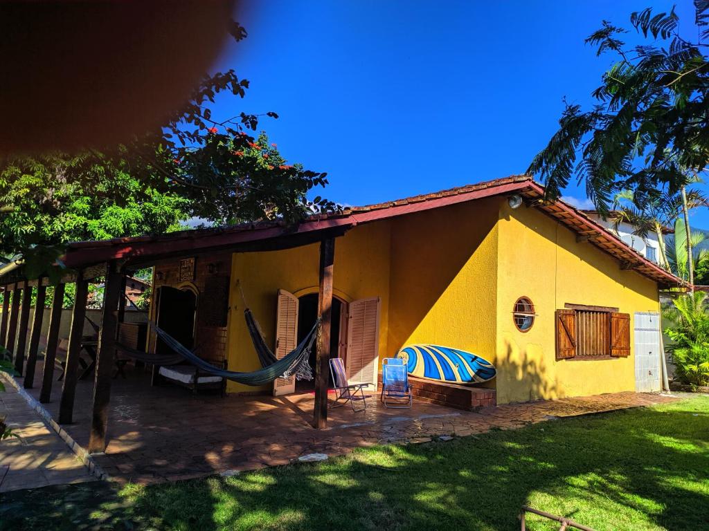 una casa amarilla con una hamaca delante en Toka do NIKO, en Ilhabela