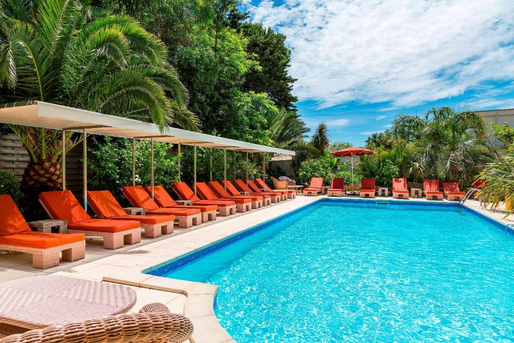 einen Pool mit orangefarbenen Liegestühlen und einem Pool in der Unterkunft Best Western Premier Montfleuri in Sainte-Maxime