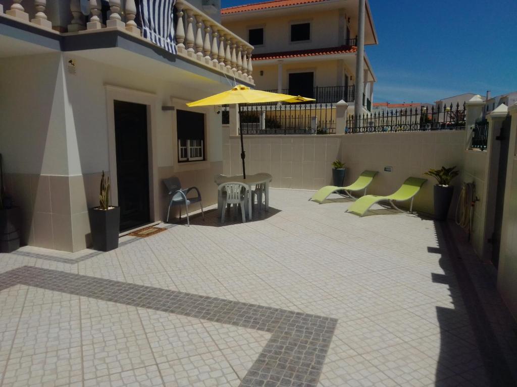a patio with a table and an umbrella on a building at HOUSEMARIA in Nazaré