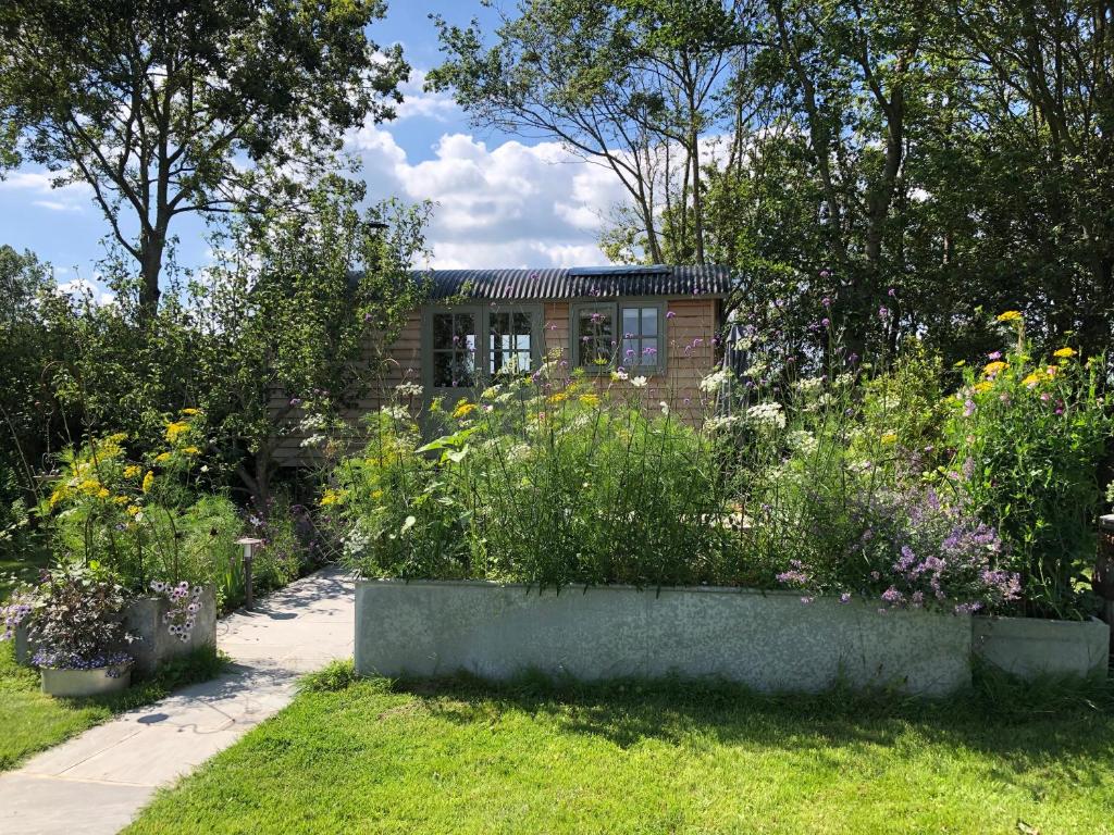 un jardín con flores frente a un edificio en Little Plovers Shepherd Hut, en Chichester