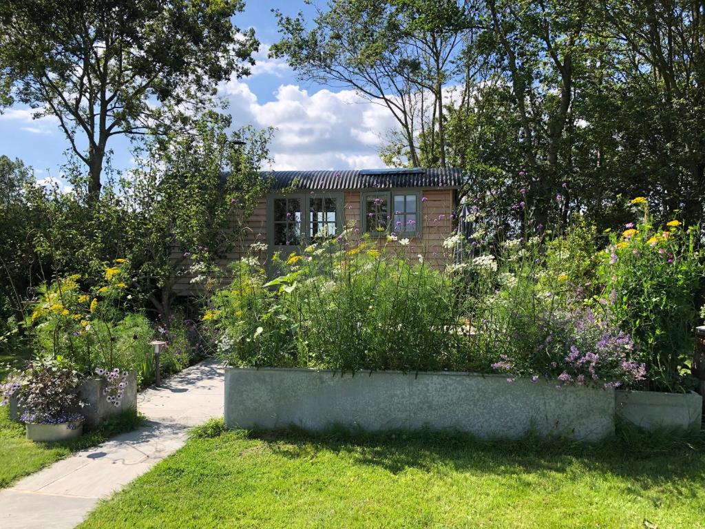 a garden with flowers in front of a building at Little Plovers Shepherd Hut in Chichester