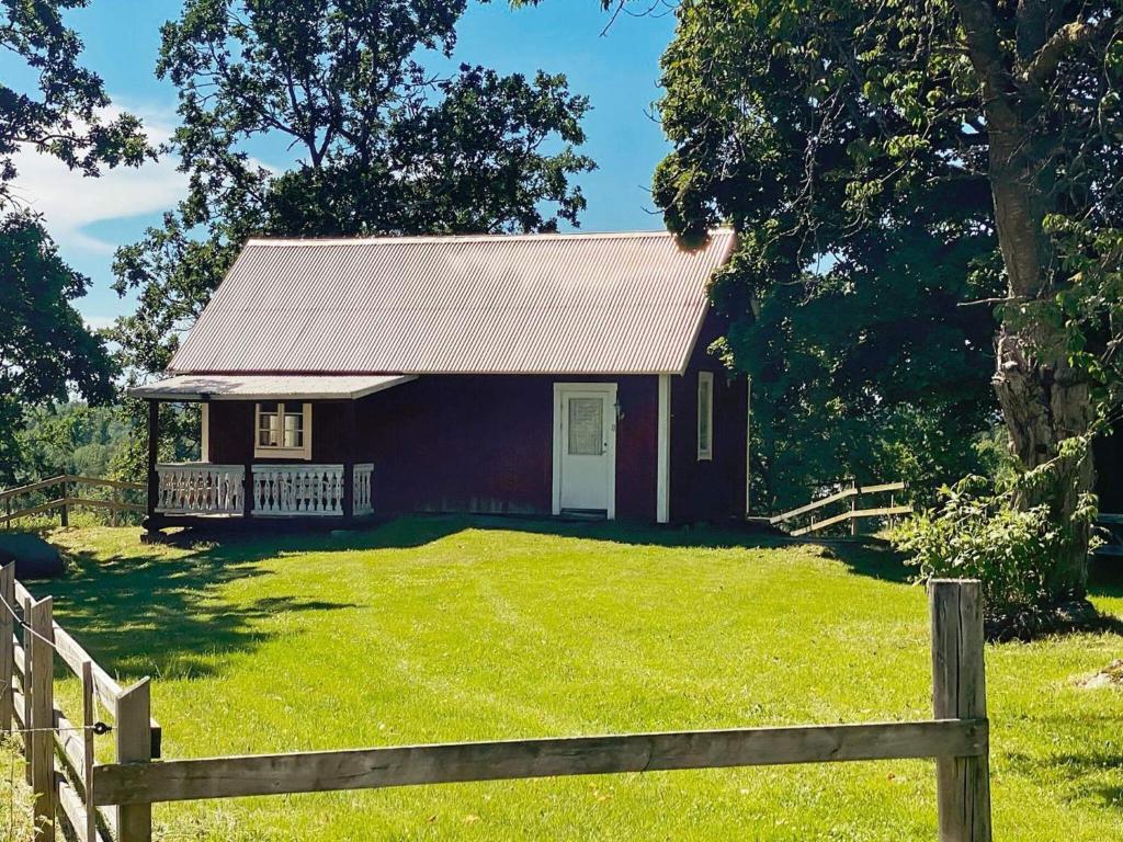 韋特蘭達的住宿－4 person holiday home in VETLANDA，一座红色的小房子,在田野上设有栅栏