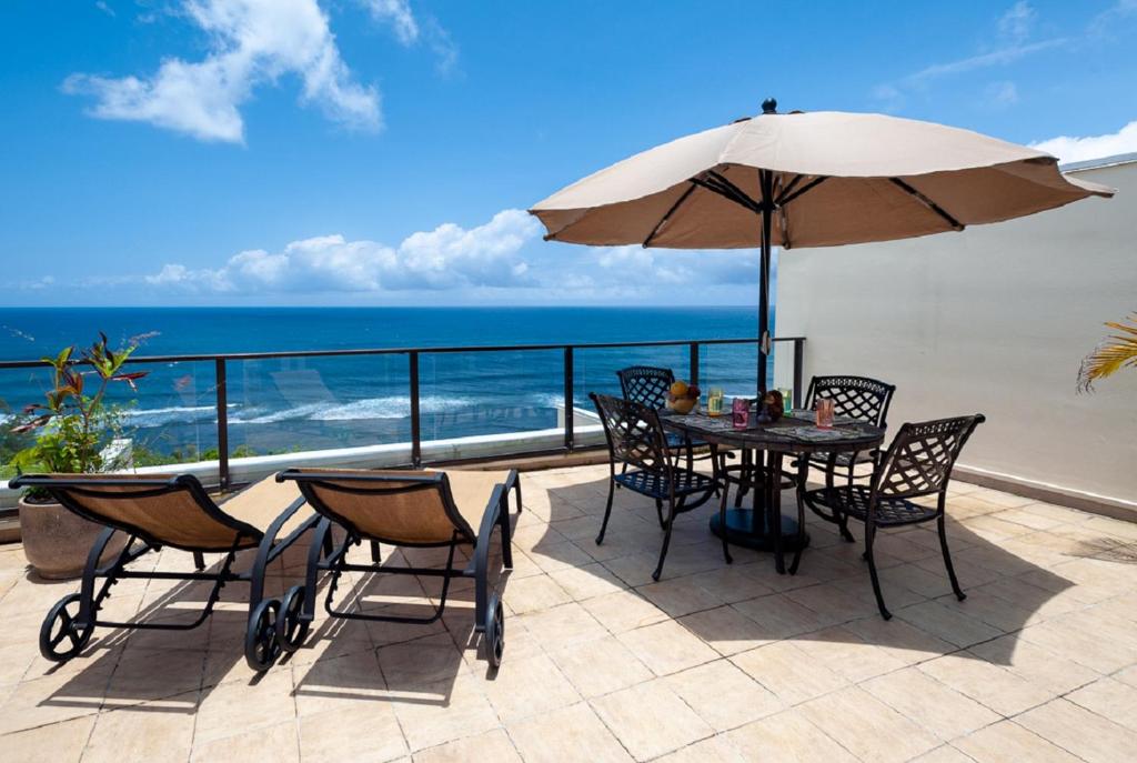 a patio with a table and chairs and an umbrella at Puu Poa 405 in Princeville