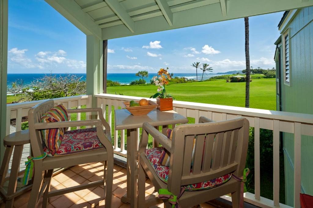 a porch with two chairs and a table with a view of the ocean at Kamahana 24 in Princeville