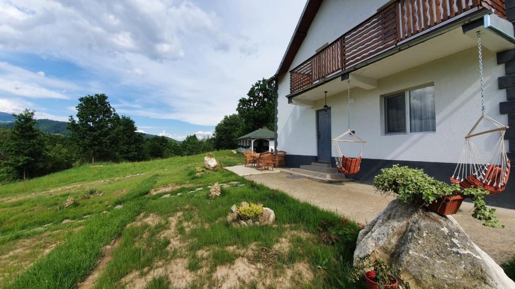 a house on a hill next to a yard at Casuta din Gradina in Horezu