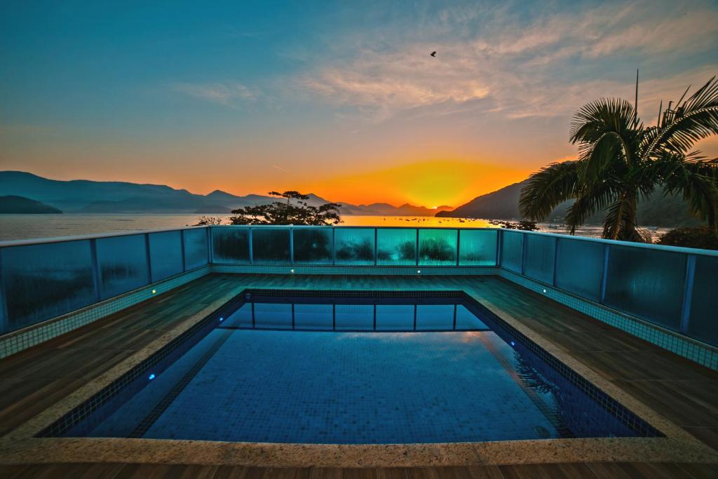 a swimming pool on the roof of a building with the sunset at Ubatuba Praia Hotel in Ubatuba