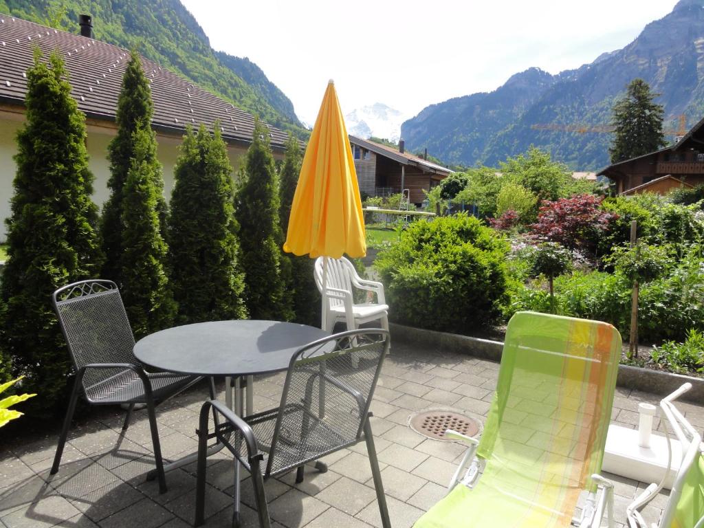 eine Terrasse mit einem Tisch, Stühlen und einem Sonnenschirm in der Unterkunft Apartment Beck in Wilderswil