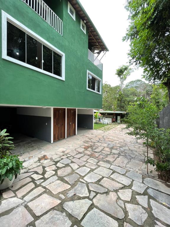 a green building with a stone driveway in front of it at Village Brasil, Lençóis in Lençóis