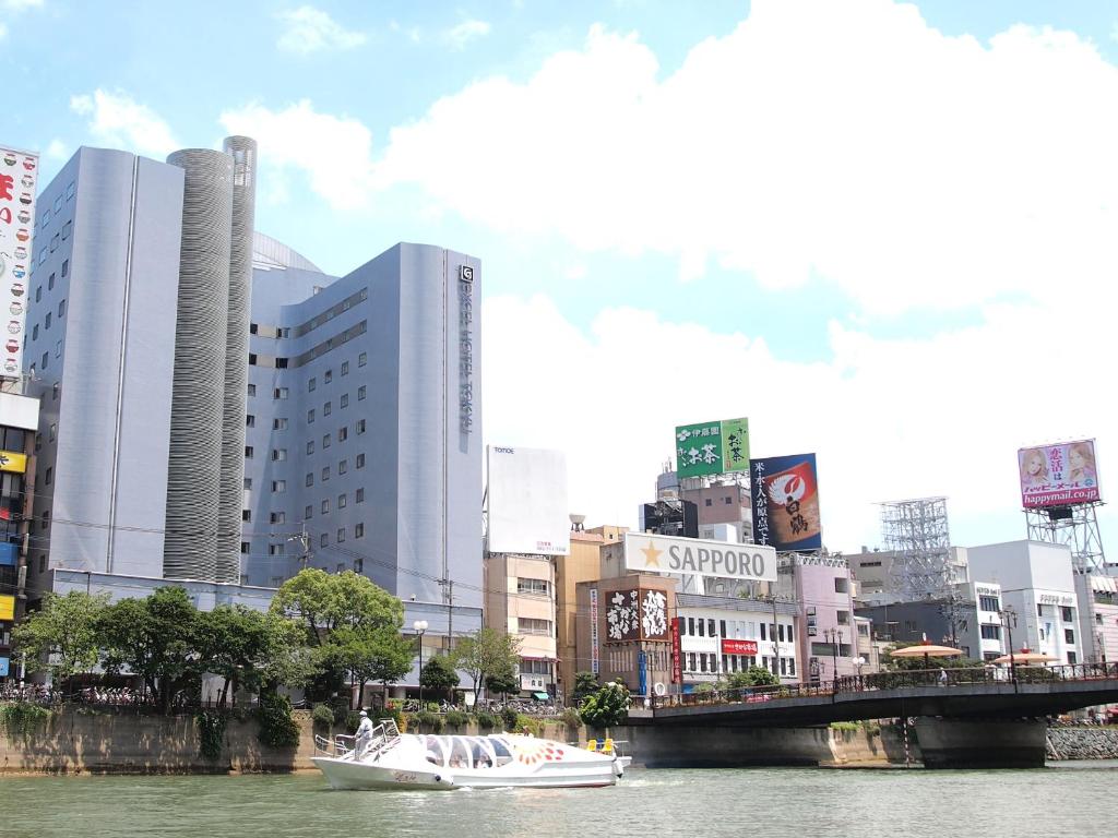 un barco en un río en una ciudad con edificios en Hakata Excel Hotel Tokyu en Fukuoka