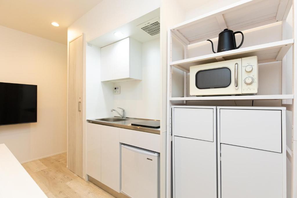 a small kitchen with a microwave and a refrigerator at Villa Roppongi in Tokyo